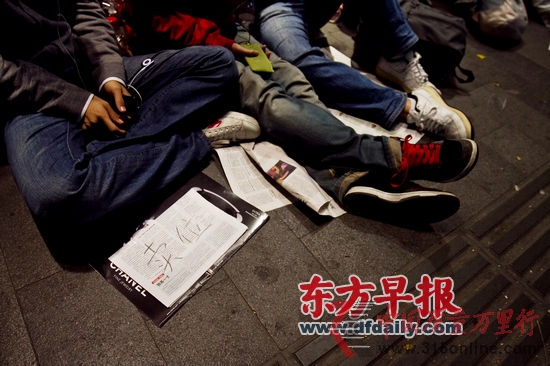 昨晚,淮海路H&M專賣店門外,一名排隊的小伙在前面放著個牌子——“賣位”。